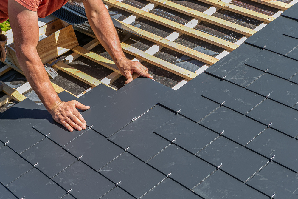 Craftsmen are installing a slate roof home.Professional roof workers installing roof for a old house .Working on rooftop.