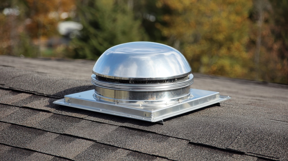 Metal static roof vent installed on an asphalt shingle roof, enabling passive attic ventilation and airflow in residential buildings.